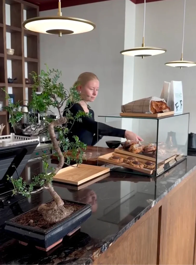 Cafe worker arranging pastries behind the counter at Kotona&Co